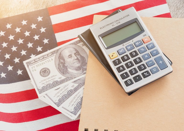 calculadora-de-la-bandera-de-los-estados-unidos-cuaderno-y-dolares-estadounidenses-sobre-un-fondo-de-madera